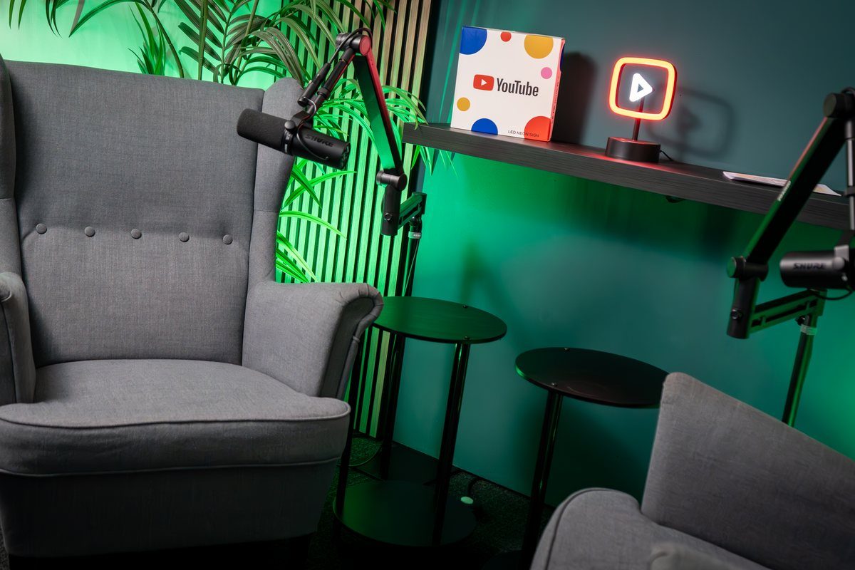 Zwei Sessel mit Mikrofonen vor grün beleuchteter Wand im Podcast Studio Bremen
